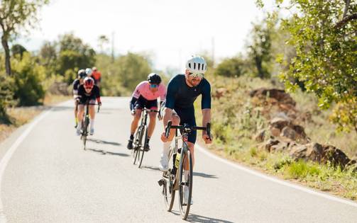 A group of cyclists pedaling along a scenic country road with lush landscapes on either side.