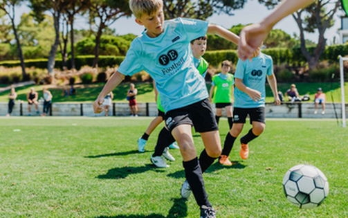 Young boys playing soccer on a grassy field at The Campus, focused on the game and enjoying their time together.