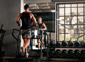 A man exercises on a treadmill in a gym, highlighting personal training services available for enhanced workouts.