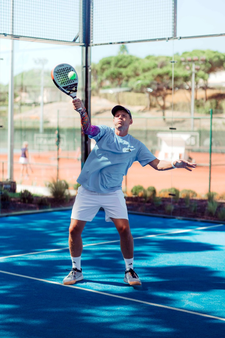 Man playing tennis at The Campus, a modern sports complex with outdoor courts surrounded by nature.